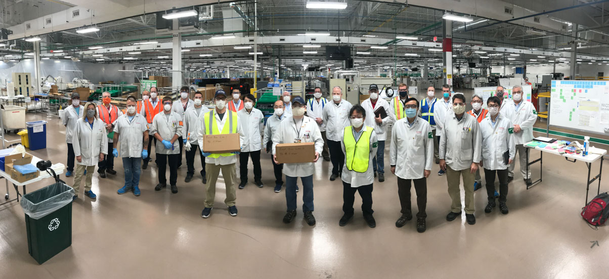 2020年にテネシー州メアリービルのデンソーで設置された臨時生産ラインから最初に出荷されたフェイスシールドの箱のひとつを、ボランティアの社員チームが手に持っている。