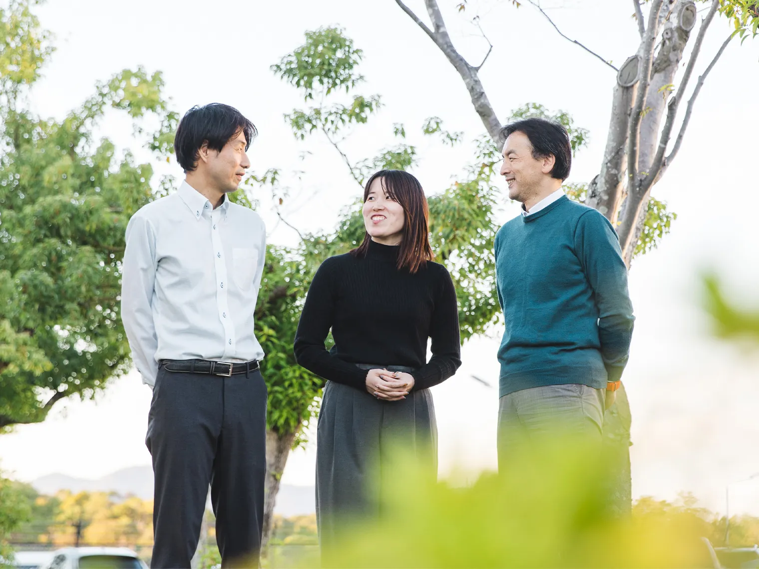 屋外で並んで会話する坂根、安部、稲葉の3名