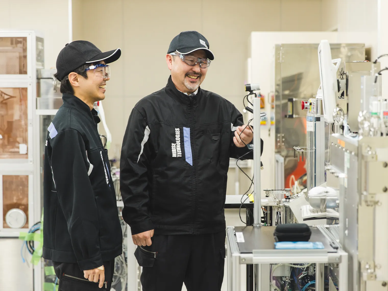 研究施設で笑顔で会話する長里と徳田