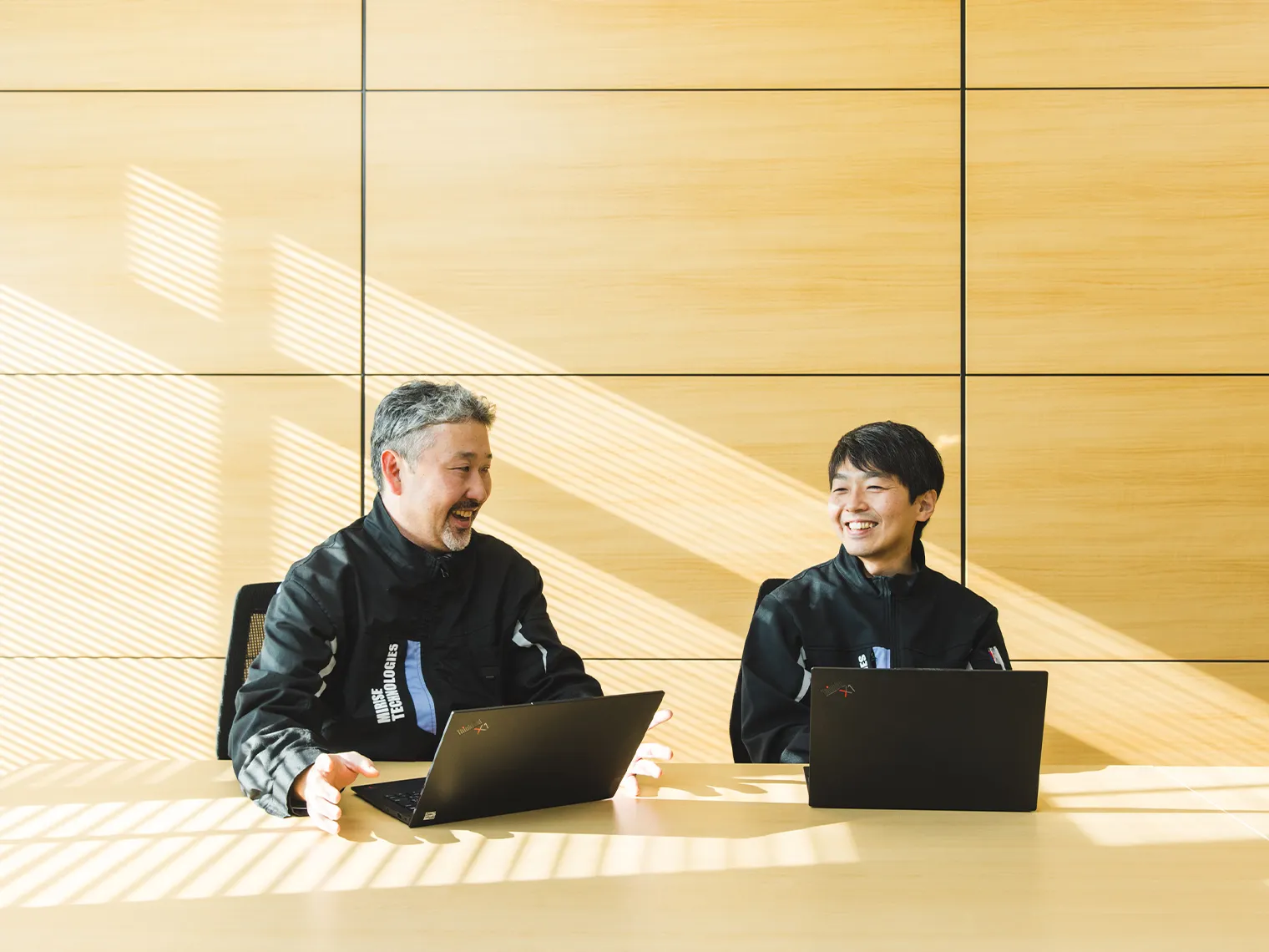 ノートパソコンを前に笑顔で対談する長里と徳田