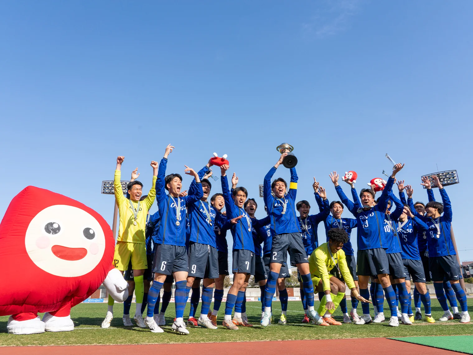 トロフィーを掲げて喜ぶ青いユニフォームを着た選手たち