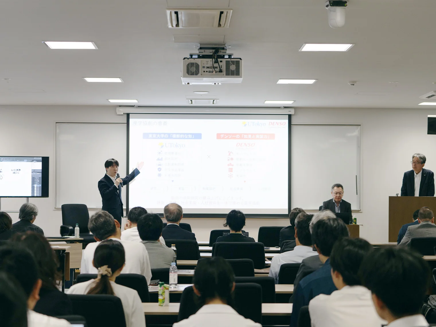 東京大学とデンソーの協創内容が映し出されたスクリーンを前に、対談イベントの参加者が聴講している様子