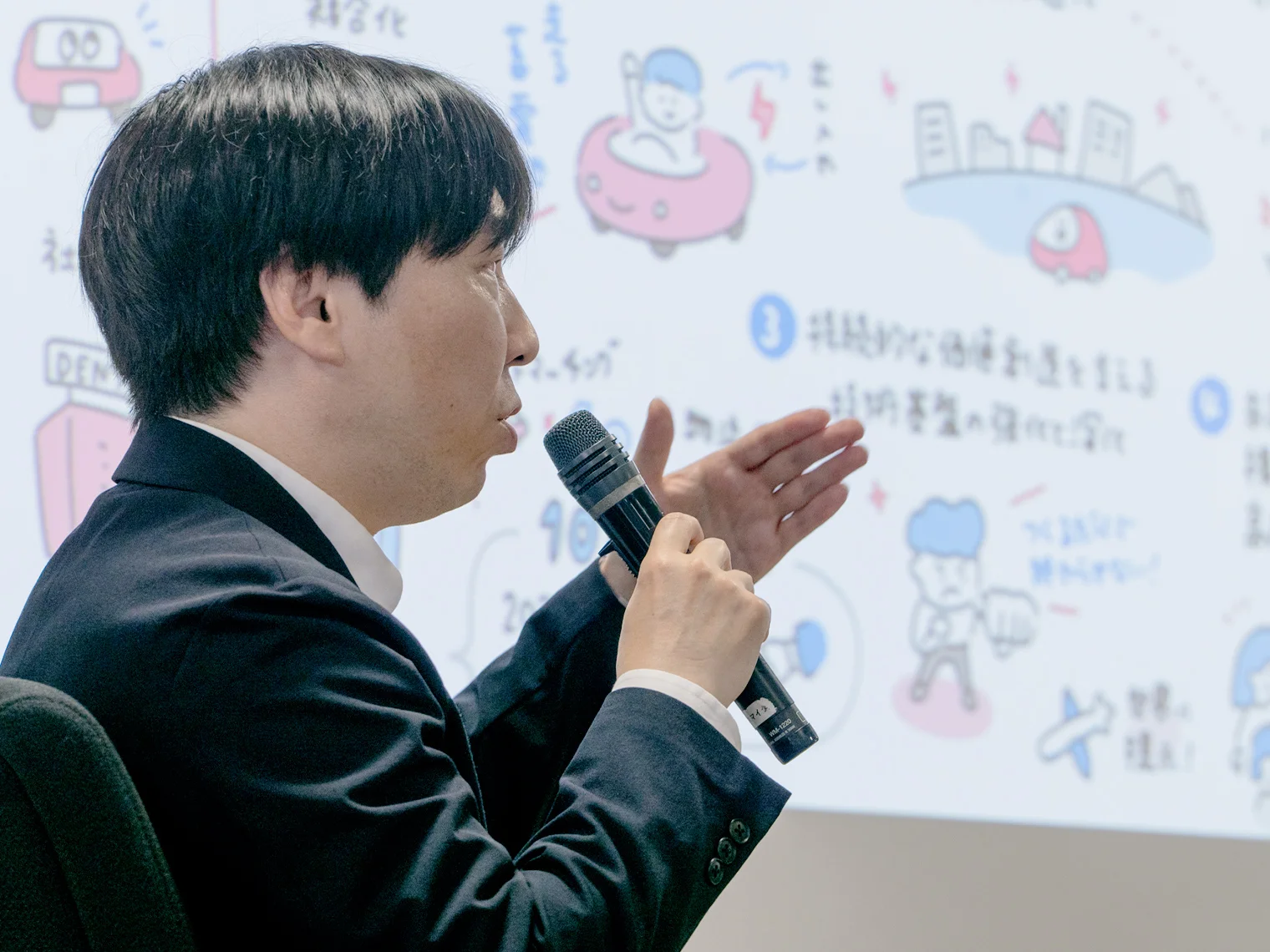 グラフィックレコーディングを指し示しながら話す本間准教授