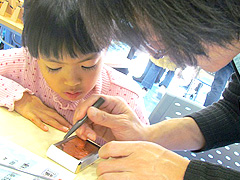 写真は、真剣な眼差しでスタッフの説明を聞いている女の子の様子