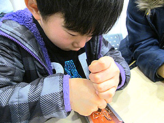 写真は、銅板をポンチで潰していますが、力を加える為に両手でポンチを押している男の子の様子