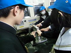 写真は、振動試験機に手で触れる生徒たちの様子