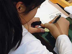 写真は、好きな形を作るために、真ちゅう板に下絵を描いている様子