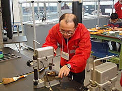 写真は、キーホルダーのリングをつける穴を、ドリルを使って開けている様子