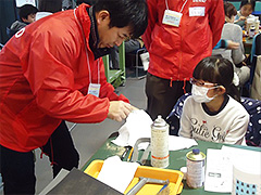 写真は、金属磨き液をつけ、布でピカピカに磨く工程の様子。