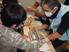 写真は、男の子が治具を使いコイルを巻いている様子