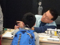 写真は、スタッフが工具について男の子に説明している様子