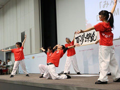 写真は、「ひゃっかりょうらん」と書いた書を広げて、ポーズを決める、ダンスチーム・MTSKの様子