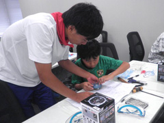 写真は、子供にロボットの作り方を教えるようぎかい会員の様子