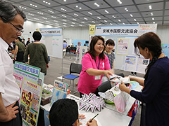 写真は、来場者に商品を手渡すNPO団体の様子