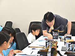 写真は、子供にロボットの作り方を教えるようぎかい会員の様子