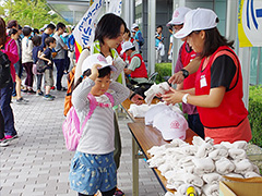 写真は、クリーン活動に必要な軍手やゴミ袋を受け取る参加者の様子