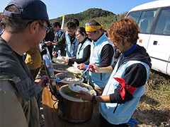写真は、みんなにカレーライスを配っている様子