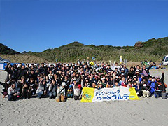 写真は、参加者全員で「おもてはまの自然を守ろう！」の掛け声に合わせ、笑顔で手をあげている参加者の様子